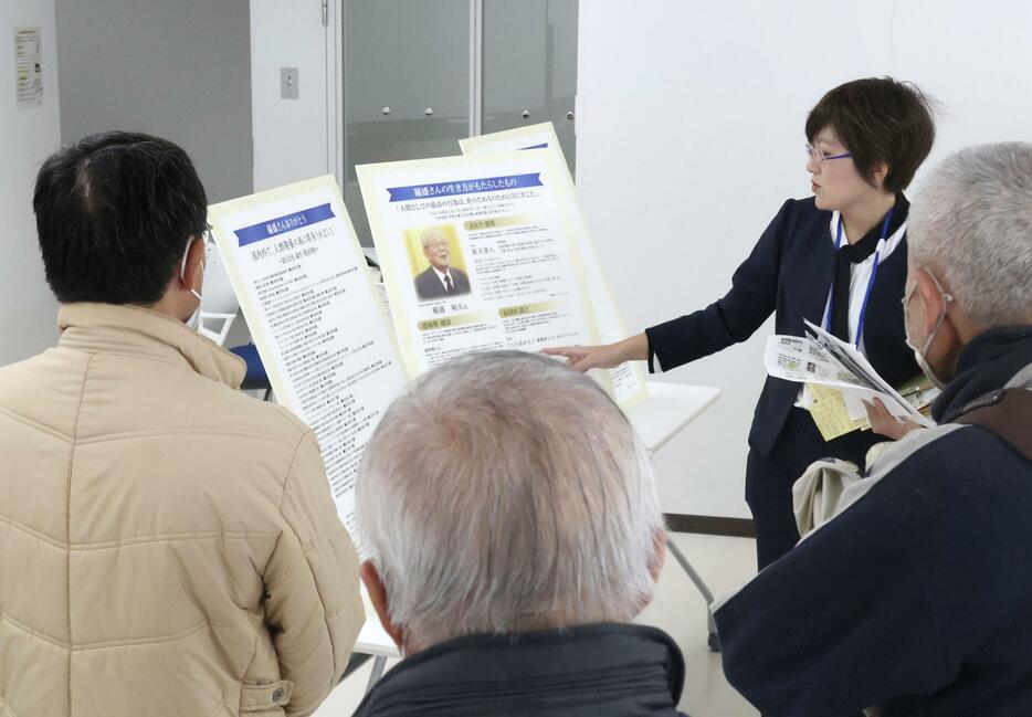 故稲盛和夫氏のパネル展で説明するデザイナーの広嶋育子さん（右奥）＝25日午前、鹿児島市