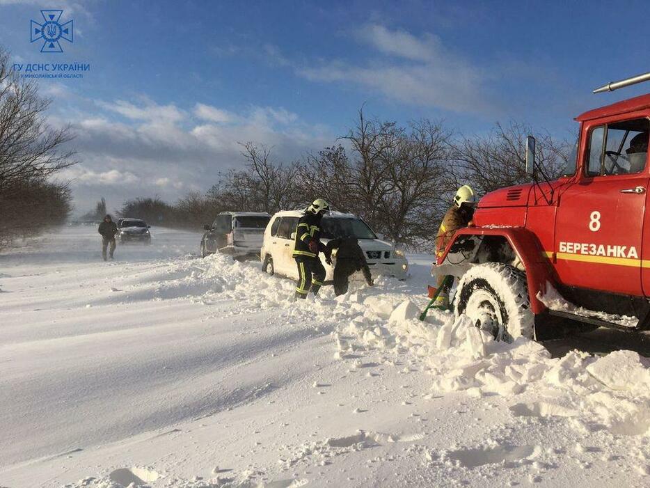 大雪に見舞われたウクライナ南部ミコライウ州で、車を引き出そうとする救助隊員ら＝27日（非常事態庁提供・ロイター＝共同）