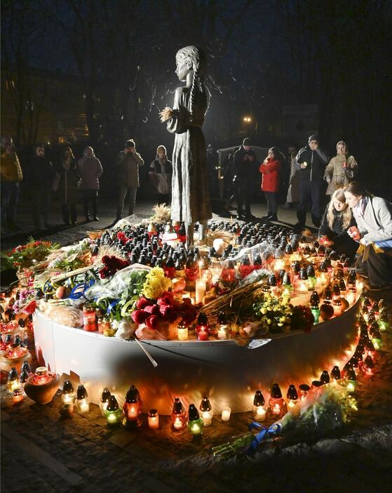 大飢饉の犠牲者を追悼する日を迎え、記念碑にろうそくを置く人たち＝25日、キーウ（共同）