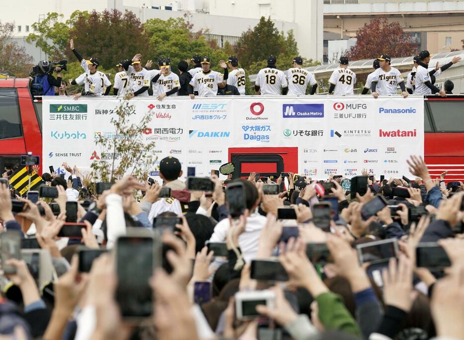 優勝パレードに詰めかけた大勢の人たちに手を振る阪神の選手ら＝23日午前、神戸市のメリケンパーク