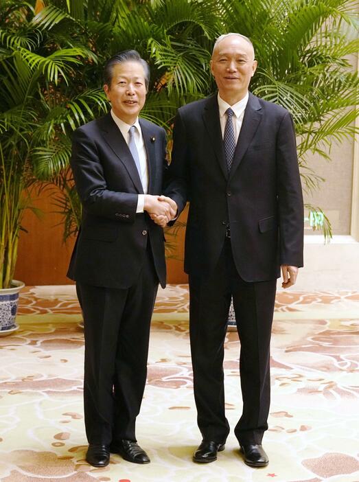 中国の蔡奇共産党政治局常務委員（右）と握手する公明党の山口代表＝22日、北京の釣魚台迎賓館（共同）