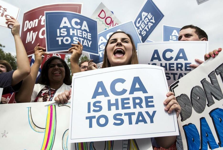 [写真]オバマ・ケアの通称「ACA（Affordable Care Act）」と書かれたプラカードで意義を訴える支持者ら（ロイター/アフロ）