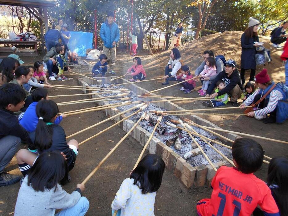 [写真]収穫祭で「焼きパン」を楽しむ子どもら