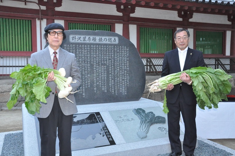 [写真]野沢菜伝来記念碑の両側に立つ野沢温泉村の富井俊雄村長（右）と天王寺蕪の会の難波利三会長＝大阪市天王寺区の四天王寺