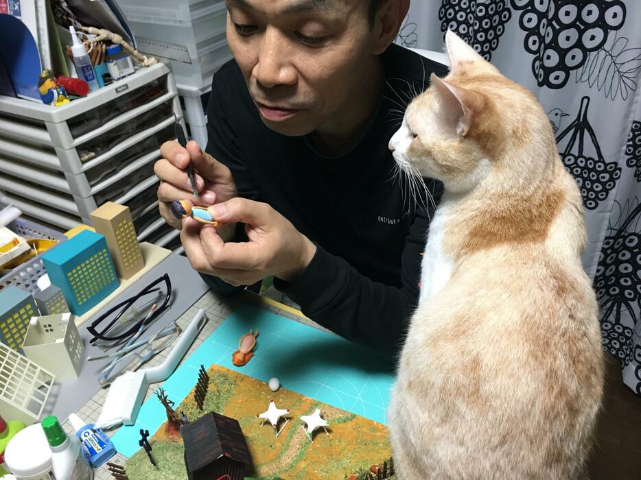 [写真]愛猫が見つめる前でクレイアニメ制作にとりかかる磯部公彦（本人提供）