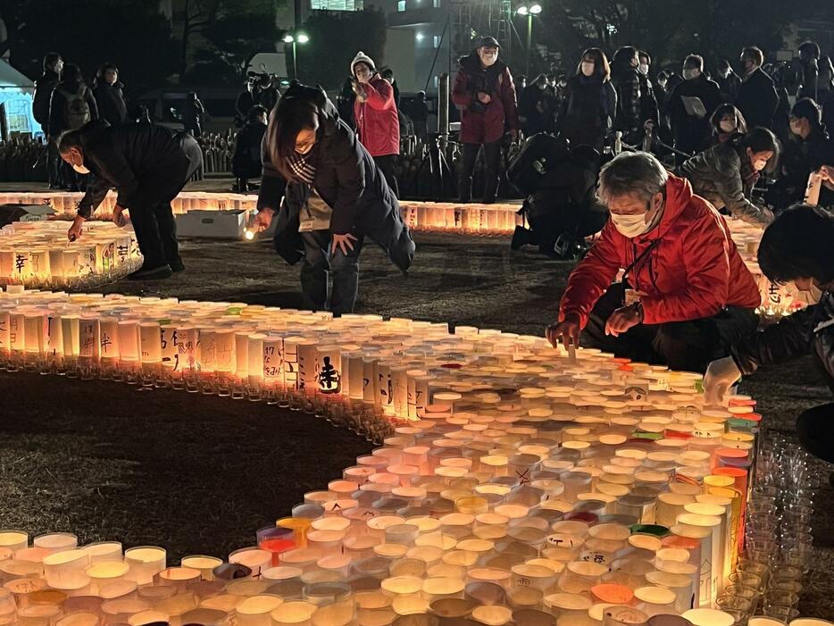 ［写真］東遊園地には午前5時ごろから多くの人が集まり、紙灯籠や竹灯籠に火を灯していた＝17日午前5時20分ごろ、神戸市中央区で