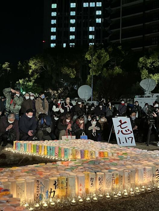 ［写真］紙灯篭に火を灯し、震災発生時刻に手を合わせて祈る人たち＝17日午前5時46分、神戸市中央区で