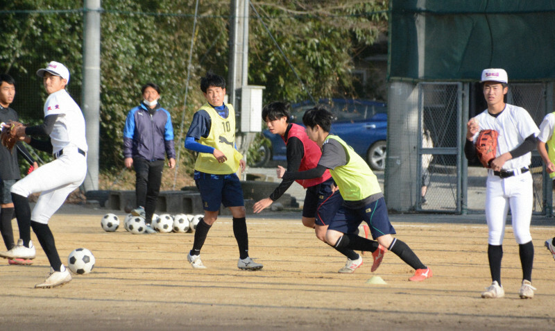 右翼側で練習するサッカー部員とグラウンドを共有しながらキャッチボールする相可の選手たち＝三重県多気町で2021年12月22日、森野俊撮影