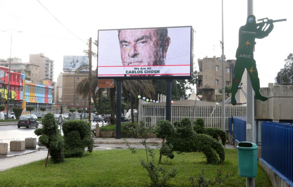 レバノンの首都ベイルートの看板に掲げられたゴーン被告の絵と「私たちはみんな、カルロス・ゴーンです」と書かれたメッセージ（写真：ロイター/アフロ）