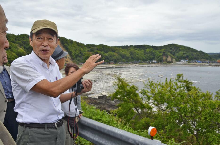 珠洲原発の建設予定地近くで隆起した海岸を前に案内する北野進さん＝12日午前、石川県珠洲市