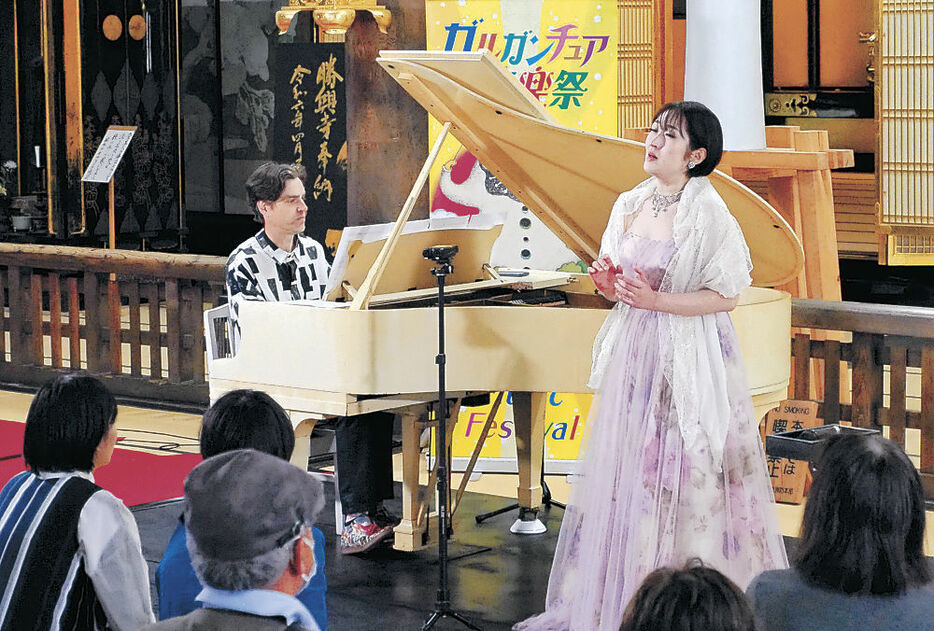 コーラーさんの演奏で伸びやかな歌声を響かせる仲谷さん（右）＝高岡市の国宝勝興寺