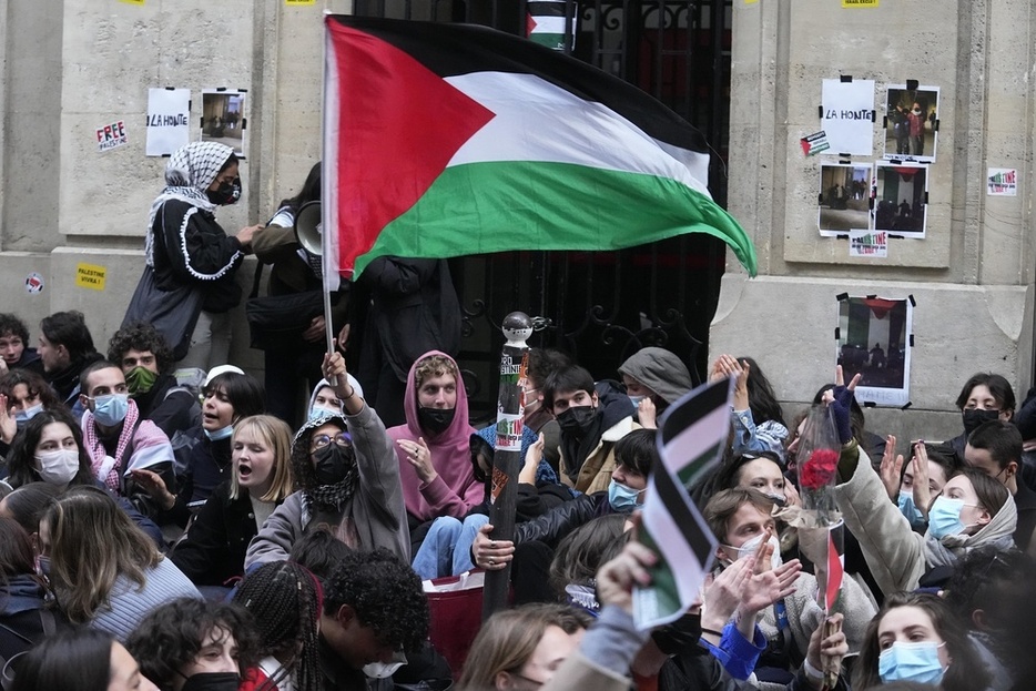 パリ政治学院の外でパレスチナの旗を振る学生＝4月、パリ（AP＝共同