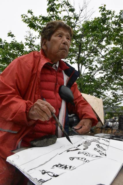 西都市の三納川の堤防近くで制作に取り組む弥勒祐徳さん＝２０１９年４月