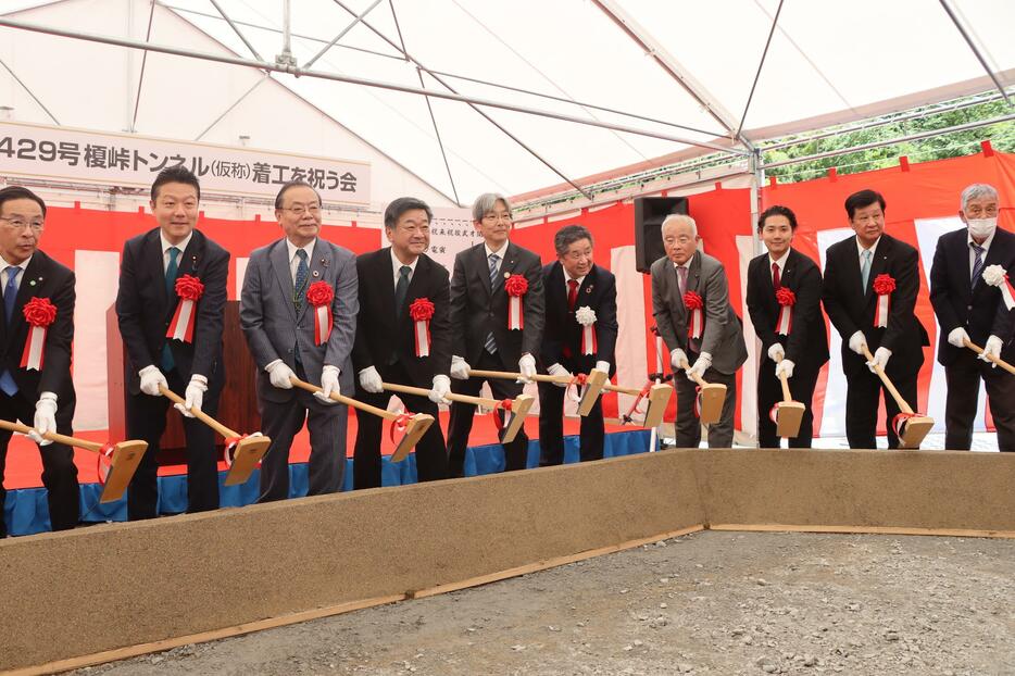 榎峠バイパスのトンネル工事着工を祝う会で、鍬入れを行う関係者たち＝京都府福知山市で