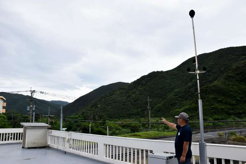 騒音測定装置近くでオスプレイの飛行ルートを示す豊島勇蔵さん＝２３日、奄美市名瀬知名瀬