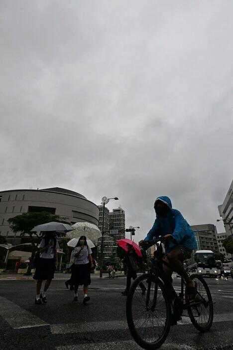 雨の中、傘を差して通勤通学する人たち＝21日午前8時33分、那覇市久茂地