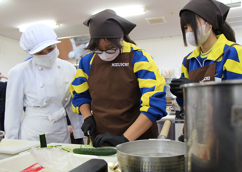 水沢一高調理科3年生（左）の指導の下、昼食を作る台湾からの短期留学生ら