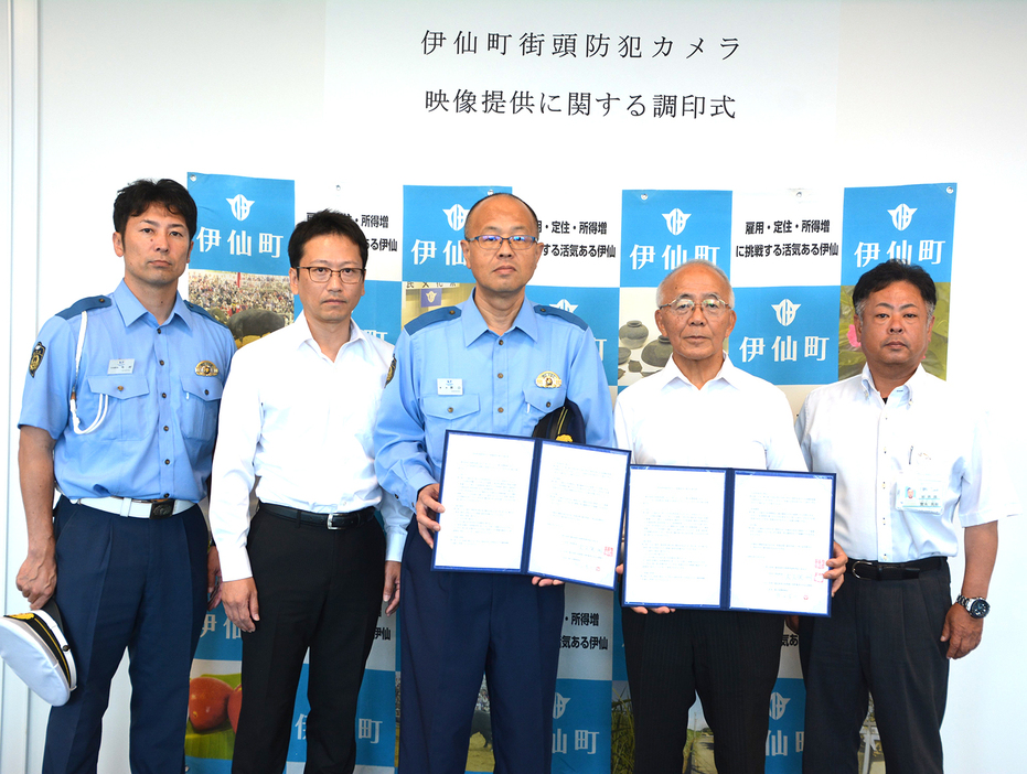 協定書を手にする大久保明伊仙町長（右から2人目）と原口浩二徳之島署長（同3人目）＝21日、同町役場