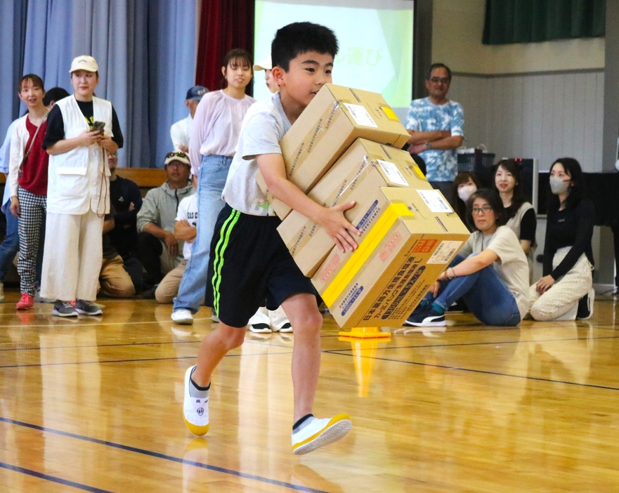 積み上げた段ボール箱を持って走る子ども。落とさないよう慎重に＝兵庫県丹波篠山市黒岡で