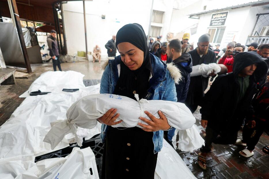 6日、パレスチナ自治区ガザ南部ラファで子どもの遺体を抱く女性（ロイター＝共同）