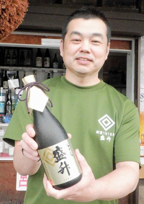 金賞を受賞した「大吟醸盛升」を持つ醸造長の飯塚栄治さん＝厚木市七沢の黄金井酒造