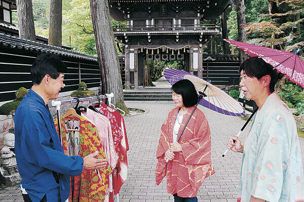観光客に羽織の無料貸し出しを案内する北川さん（左）=小松市の那谷寺