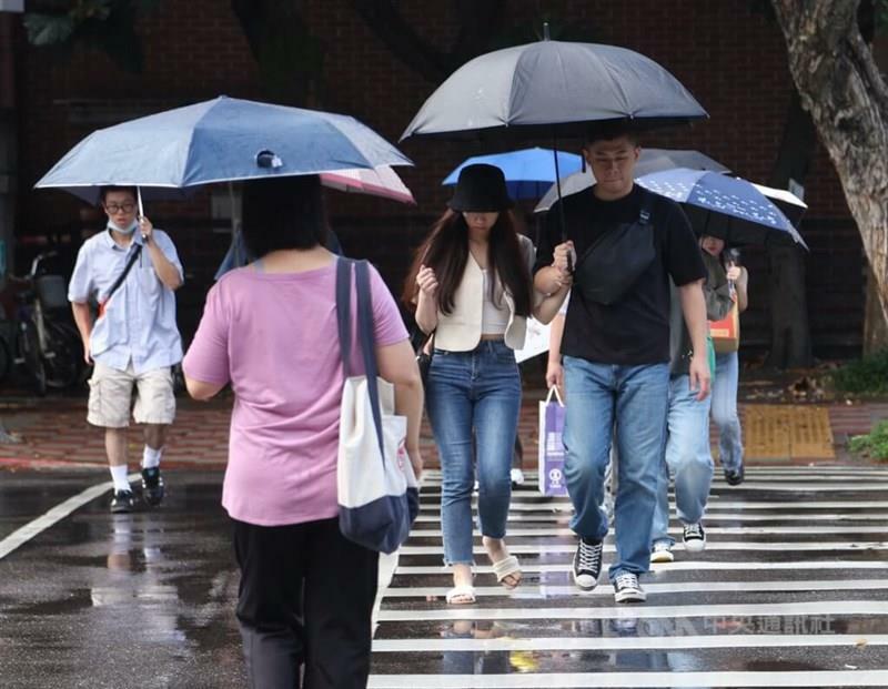 雨の中、傘を差して横断歩道を渡る人たち＝資料写真