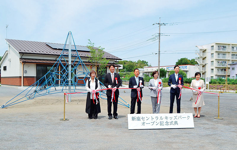 オープン記念式典でクライミング遊具の前でテープカットする新座市町内会連合会の清水由紀子会長（左から）、安藤友貴県議、並木傑市長、島田久仁代・市議会議長、平松大佑県議、嶋野加代市議＝新座市道場1丁目