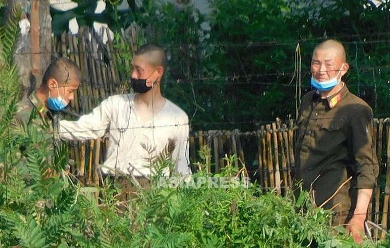 有刺鉄線の内側で警備する若い兵士たち。マスクで鼻を覆うのが面倒なのはどこも同じようだ。2021年7月、新義州市を中国側から撮影（アジアプレス）