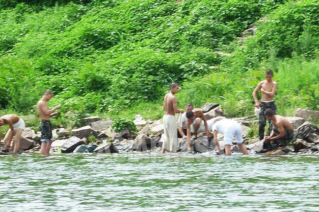 鴨緑江のほとりで入浴と洗濯をする若い兵士たち。みんな痩せている。2017年7月に平安北道朔州郡を中国側から石丸次郎撮影。（アジアプレス）。