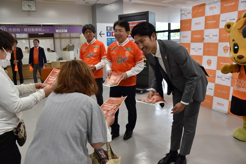 来庁者にチラシを渡す渡部社長（右）ら（市役所で）