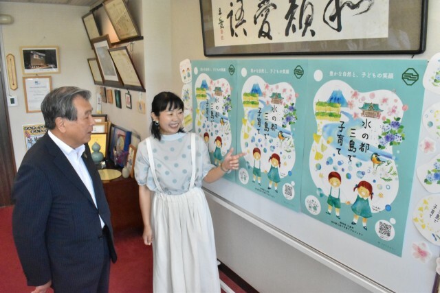 シンボルデザインについて豊岡市長（左）に説明するえがしらさん＝三島市役所