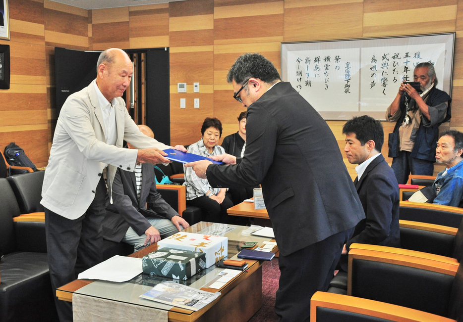 栃木市長から預かった親書を奄美市に届けた田中一村記念会の大木洋三会長（左）＝27日、鹿児島県奄美市名瀬