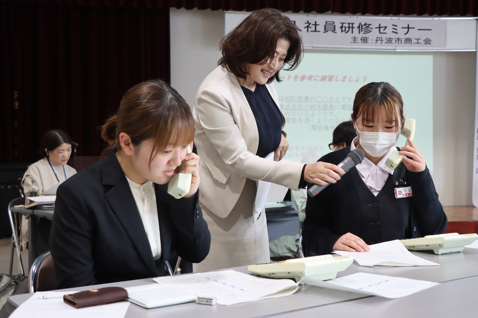 樽口さんが見守る中、適切な電話応対を実演する若手社員たち＝兵庫県丹波市氷上町成松で