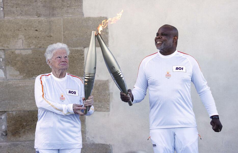 フランス南部マルセイユで始まったパリ五輪の聖火リレーで、聖火を次の走者に点火するバジール・ボリ氏（右）＝9日（共同）