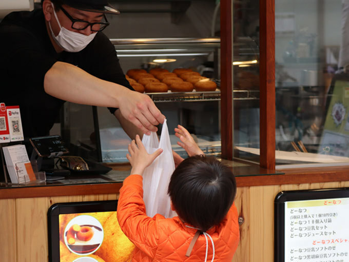 おつかい体験サービスで、両親から頼まれたドーナツを買う男の子＝2024年3月24日、東京都足立区