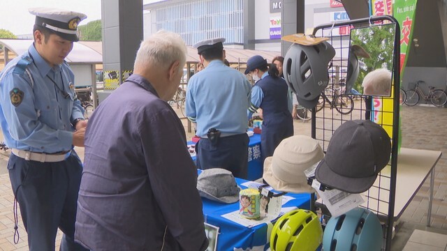 警察官が自転車販売店でヘルメット着用の啓発活動