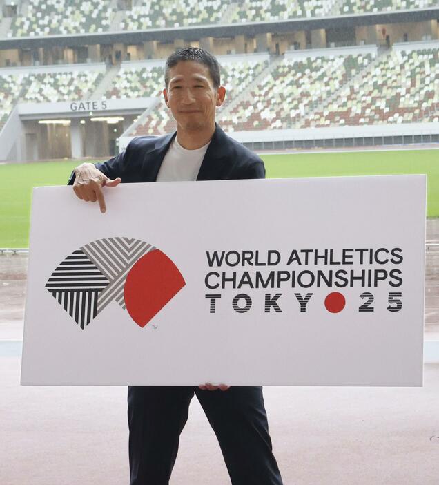 東京で開催される陸上世界選手権の大会ロゴを手にする中川亮さん＝13日、東京・国立競技場