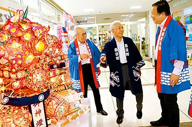 点灯したミニ行燈の前で「となみ夜高まつり」の魅力を語り合う（左から）堀田会長、渡辺さん、夏野市長