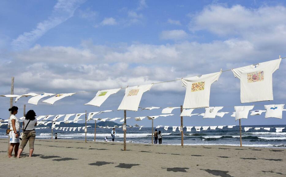 高知県黒潮町の砂浜で洗濯物を干すように並べて展示されたTシャツ＝2日午後