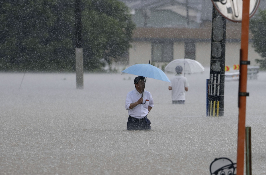 大雨の影響で冠水した道路を歩く人＝2023年7月10日、福岡県久留米市