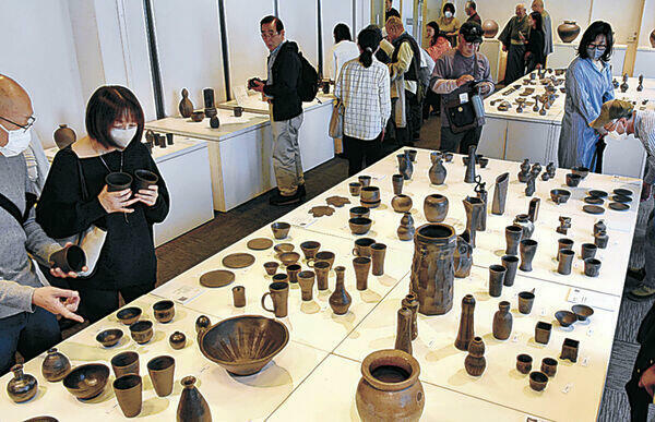 珠洲焼の作品を品定めする来場者=金沢市のしいのき迎賓館