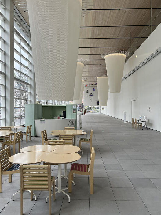 大分県立美術館（OPAM）1階アトリウム。ガラス張りの開放的な空間が心地良い。手前のカフェスペースの向こうには須藤玲子の『水分峠の水車』が展示されている。
