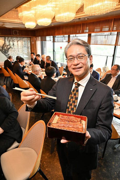 「100万円」のうな重を手に微笑む新日本科学・永田良一社長