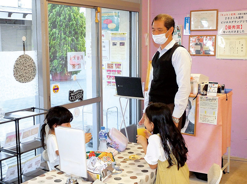 「Kuki紅茶」で子どもたちに飲み物を提供するマスターの伊藤康之さん＝17日午後、久喜市上内