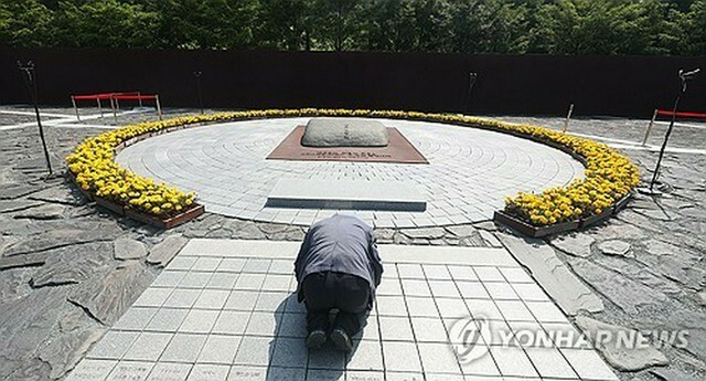 盧武鉉元大統領の墓前で頭を下げる市民＝23日、金海（聯合ニュース）