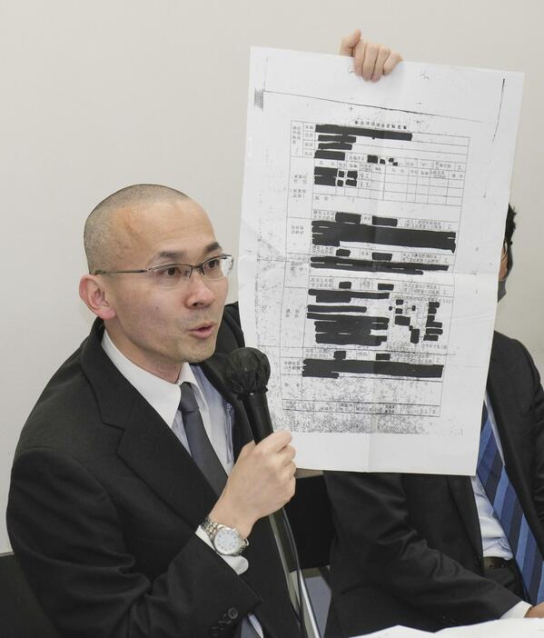 判決後の記者会見で、滋賀県側が開示した大半が黒塗りの文書を示す京都新聞の森敏之記者＝9日午後、大阪市