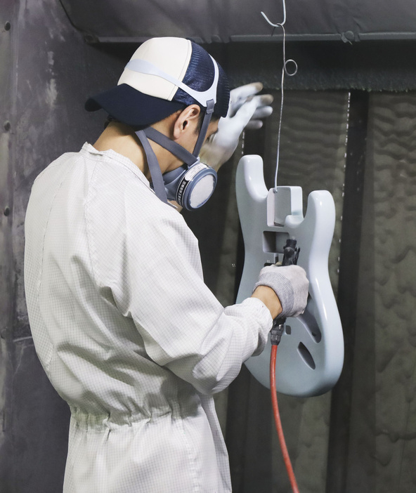 「オホーツク楽器工業」でエレキギターのボディーに塗装をする職人＝北海道西興部村（2024年4月）
