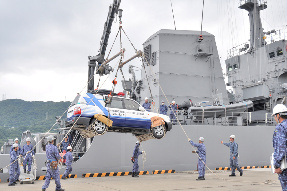 クレーンで岸壁に降ろされる車両＝25日、鹿児島県奄美市名瀬の名瀬港