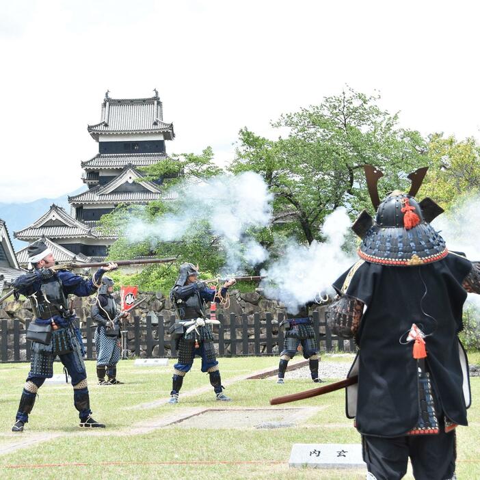 松本城天守を望む二の丸御殿跡で火縄銃で空砲を撃つ隊員たち